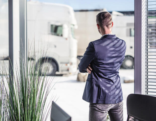 Male worker in Melbourne office looking out over a fleet of vehicles after discussing equipment finance