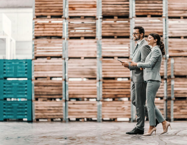 Two business people in a Melbourne warehouse smiling and discussing their business and corporate finance solutions